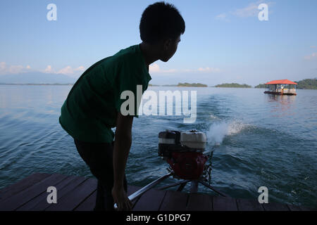 Nam Ngum See.  Junge Lenkung eine traditionelle Lao-Motorboot. Laos. Stockfoto