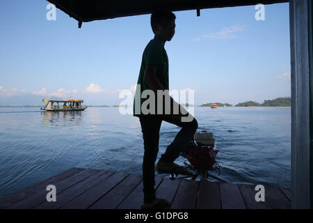 Nam Ngum See.  Junge Lenkung eine traditionelle Lao-Motorboot. Laos. Stockfoto