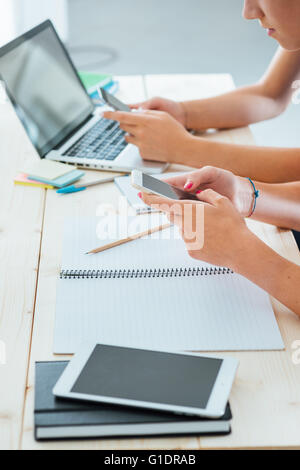 Teenager Studentinnen am Schreibtisch sitzen, con studieren und mit Touch Screen Smartphones, Jugendkultur und Telekommunikation Stockfoto