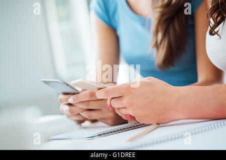 Teenager Studentinnen am Schreibtisch sitzen, con studieren und mit Touch Screen Smartphones, Jugendkultur und Telekommunikation Stockfoto
