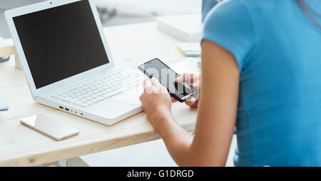 Teenager-Mädchen am Schreibtisch sitzen und per Smartphone, unerkennbar person Stockfoto