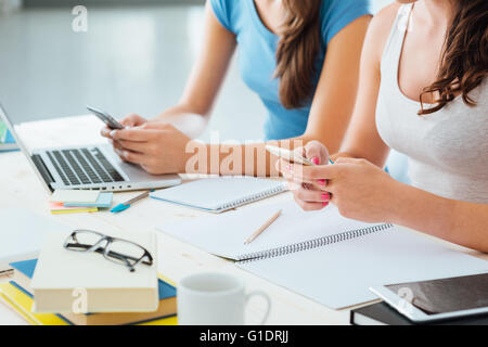 Teenager Studentinnen am Schreibtisch sitzen, con studieren und mit Touch Screen Smartphones, Jugendkultur und Telekommunikation Stockfoto