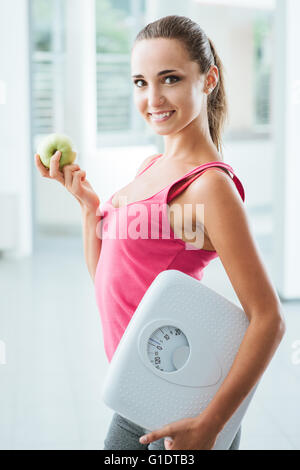 Lächelnde Teenager-Mädchen mit einer Skala und einen frischen Apfel, gesunde Ernährung, Fitness und Gewicht-Verlust-Konzept Stockfoto