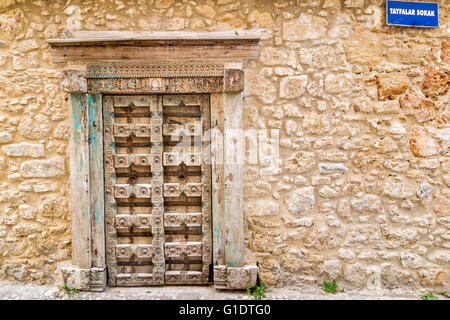 NORD ZYPERN KYRENIA ALTSTADT GESCHNITZTE HOLZTÜR UND ALTE STEINERNE WAND MIT STRAßENSCHILD TAYFALAR SOKAK Stockfoto