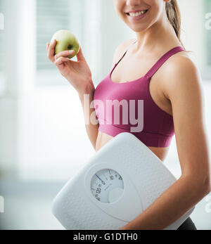 Lächelnde Teenager-Mädchen mit einer Skala und einen frischen Apfel, gesunde Ernährung, Fitness und Gewicht-Verlust-Konzept Stockfoto