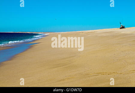 Ein einsamer Fischer sitzt am Strand arbeitet an seinem Gang bei Las Palmas Strand in der Nähe von Todos Santos, Baja Sur, Mexiko. Stockfoto