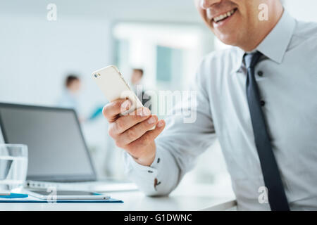 Geschäftsmann, sitzen am Schreibtisch im Büro über ein Touchscreen-Smartphone, Hände hautnah, Büro Interieur und Business Leute auf Rückseite Stockfoto