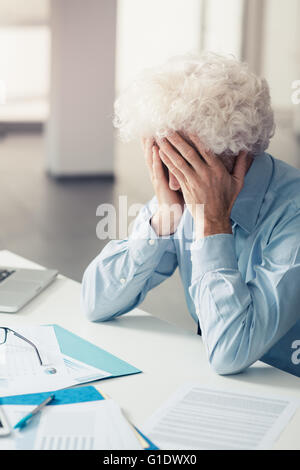 Erschöpften Geschäftsmann mit Kopf in Händen sitzen am Schreibtisch, Störung und Depressionen Bürokonzept Stockfoto