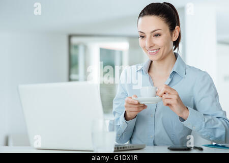 Lächelnde Frau, die gerade ein Video auf ihrem Laptop während einer Kaffeepause Stockfoto