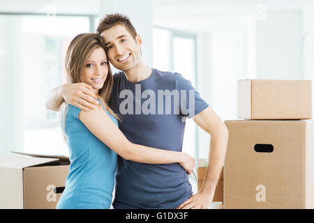 Junges Paar glücklich umarmt in ihrem neuen Haus und lächelt in die Kamera Stockfoto