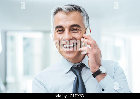 Zuversichtlich Geschäftsmann mit einem Telefonanruf und lächelt in die Kamera Stockfoto