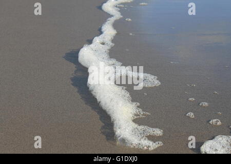 Schaum-links von Surf an einem Strand in einem ruhigen Tag in Piha, Neuseeland Stockfoto