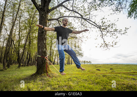 Mann zu Fuß Slacklinen und balancieren auf einem Seil Stockfoto