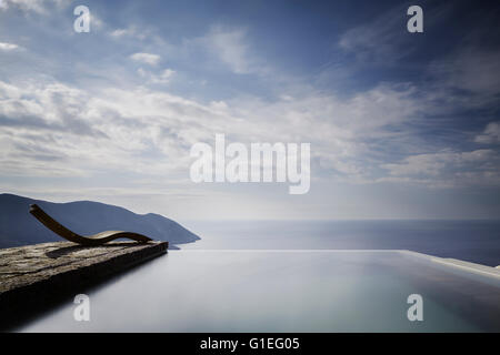 Tenaro blau Retreat in Mani, Griechenland. Blick auf eine Liege auf einer steinernen Terrasse neben dem Pool und mit Blick auf die Küste. Stockfoto