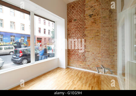 Buro, 53 Reichenberger Straße. Leere Zimmer mit großem Fenster und Backstein-Mauer. Boden und Glas Holztür. Stockfoto