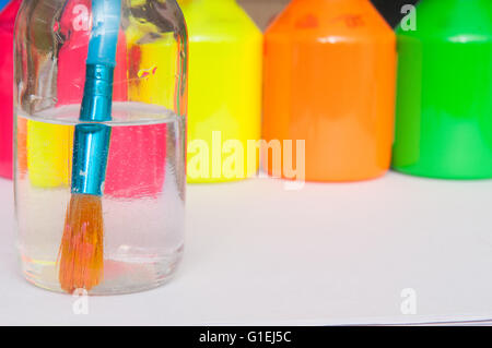 Pinsel in Wasser vor bunten Kinder Farbtöpfe für einen regnerischen Tagesaktivität Stockfoto