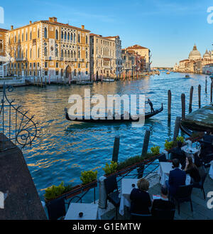 Gondel mit Gondoliere am Canal Grande in Venedig, mit Außengastronomie im Vordergrund Stockfoto