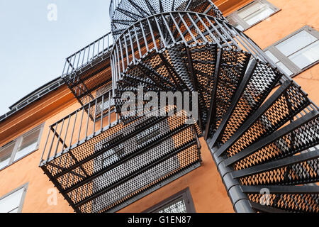 Abstrakt Architektur Fragment, wieder Metallspirale Leiter auf die rote Wand Stockfoto