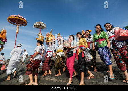 Farbenfrohe Prozession der indonesischen Frauen des Balinese hinduistischen Glaubens tragen religiöse Angebote auf einem Strand in Bali Stockfoto