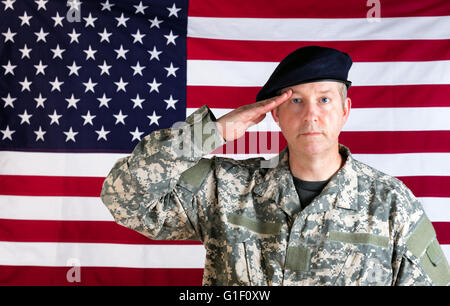 Erfahrene Soldat, nach vorne gerichtet, grüßte mit USA-Flagge im Hintergrund. Stockfoto