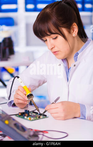 -MODELL VERÖFFENTLICHT. Weibliche Elektrotechniker Prüfung einer Leiterplatte. Stockfoto