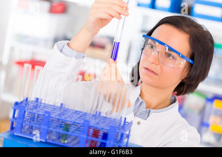 -MODELL VERÖFFENTLICHT. Wissenschaftlerin mit einem Reagenzglas. Stockfoto