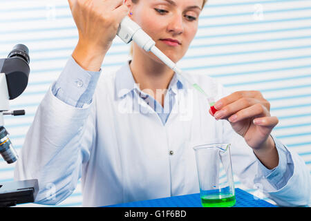 -MODELL VERÖFFENTLICHT. Weiblichen Chemiker mit Pipette im Labor. Stockfoto