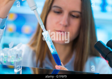 -MODELL VERÖFFENTLICHT. Wissenschaftlerin mit Hilfe einer Pipette und Reagenzglas. Stockfoto