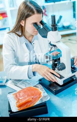 -MODELL VERÖFFENTLICHT. Wissenschaftlerin Lachs unter dem Mikroskop zu studieren. Stockfoto