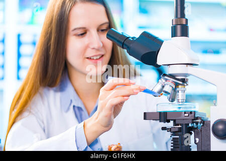 -MODELL VERÖFFENTLICHT. Wissenschaftlerin mit Mikroskop im Labor. Stockfoto