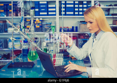 -MODELL VERÖFFENTLICHT. Weiblichen Chemiker, der auf einem Laptop im Labor arbeitet. Stockfoto