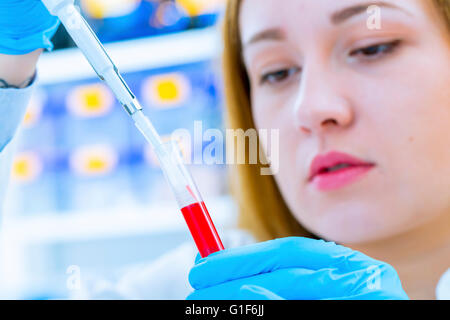 -MODELL VERÖFFENTLICHT. Wissenschaftlerin ein Reagenzglas halten und mit Hilfe einer Pipette. Stockfoto