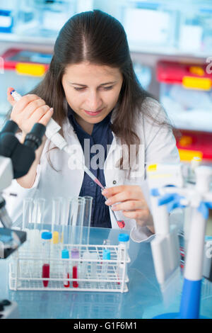 -MODELL VERÖFFENTLICHT. Weibliche Laborantin mit einer Pipette im Labor. Stockfoto