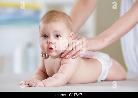 Mutter Massage Baby im Bett zu Hause Stockfoto