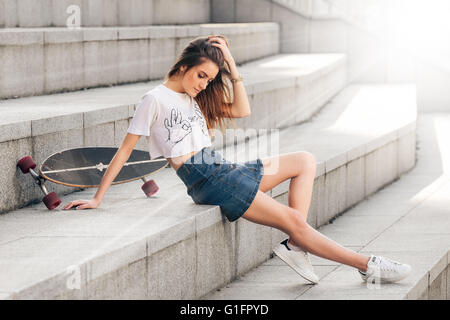 Porträt des jungen schöne modische Mädchen posiert auf Betontreppen Stockfoto