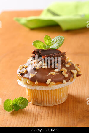 Nahaufnahme von Schoko-Muffin mit gehackten Nüssen auf Holztisch Stockfoto