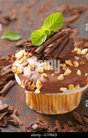 Nahaufnahme von Schoko-Muffin mit gehackten Nüssen auf Holzbrett Stockfoto