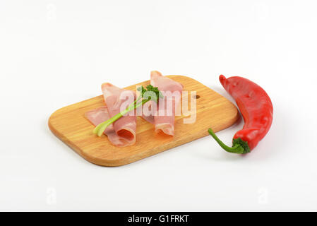 Scheiben vom Schweineschinken mit Petersilie und Paprika auf Holzbrett Stockfoto