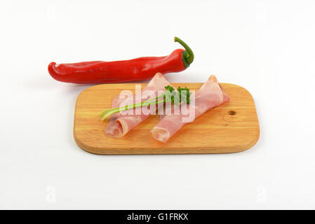 Scheiben vom Schweineschinken mit Petersilie und Paprika auf Holzbrett Stockfoto