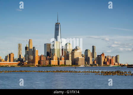 New York City Manhattan Financial District Wolkenkratzer und Hudson River mit hölzernen Pfählen bei Sonnenuntergang Stockfoto