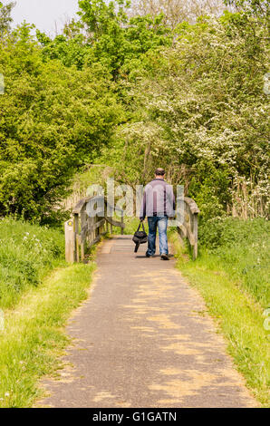 Ein Mann geht über eine Holzbrücke, wie er auf einem öffentlichen Wanderweg geht entlang dem Fluss Kennet in Reading, UK Stockfoto