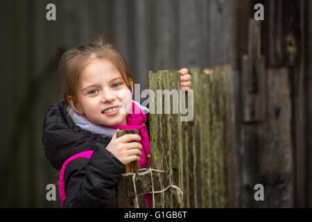 Porträt der kleine süße Mädchen in der Nähe des Zauns im Dorf. Stockfoto