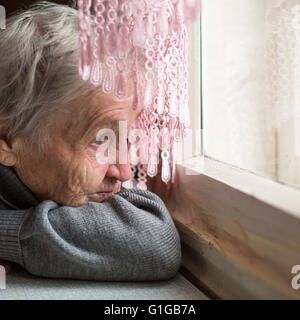 Alte Frau wehmütig starrte aus dem Fenster. Stockfoto