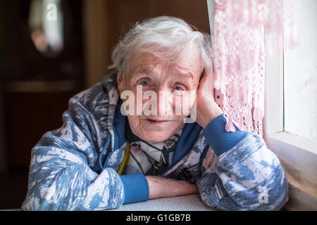 Closeup Portrait Seniorin, die am Tisch sitzen. Stockfoto