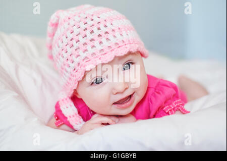 Neugeborenes Babymädchen in Rosa Mütze auf dem Bett Stockfoto