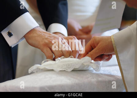 Bräutigam und Priester Hände unter Ehering Stockfoto