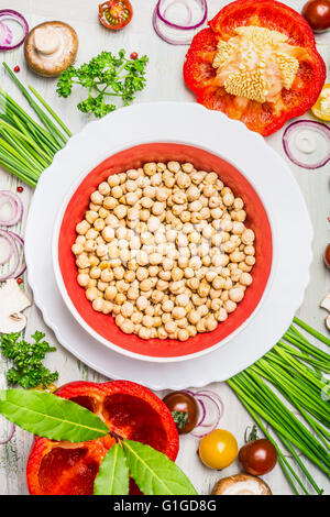 Hummus-Teller und verschiedene Gemüse und Gewürz-Zutaten für leckere vegetarisch Kochen auf rustikalen hölzernen Hintergrund, Stockfoto