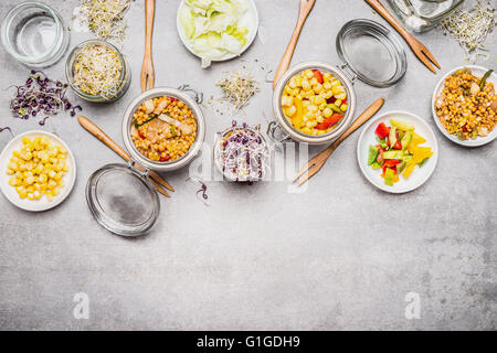 Gesunde vegetarische Mais Salate. Verschiedenen Salat in Gläsern auf grauem Stein Hintergrund. Mittagessen in Gläsern. Stockfoto