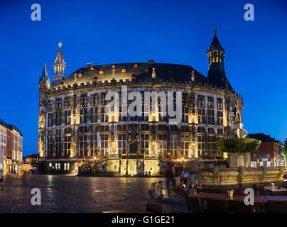 Panoramablick auf das historische Rathaus von Aachen, Deutschland mit blauen Nachthimmel und der Karlsbrunnen im Vordergrund. Stockfoto