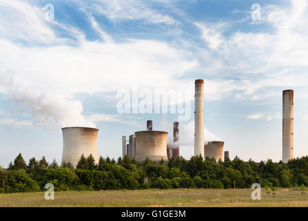 Eine große Kohle-Kraftwerk hinter einigen Bäumen und einem Feld. Stockfoto